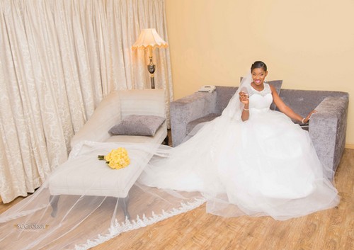 bride poses in short-sleeved wedding gown snd yellow bouquet